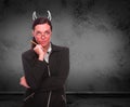 Devil Horns Drawn on Head of Red Faced Young Adult Woman with Pencil In Front of Grungy Wall with Copy Space Royalty Free Stock Photo