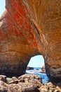 Devil`s Punchbowl Cave interior with red clay deposits looking out into Pacific Ocean waves Royalty Free Stock Photo