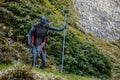 Devil statue next to castle Trosky on sunny day, devil with trident on hill, green grass, iron demon in black and red cloak with