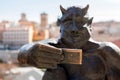 Devil statue taking a selfie against the ancient Roman aqueduct of Segovia, Spain