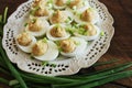 Deviled eggs with cod livers with leek on white plate. Rustic wooden table Royalty Free Stock Photo