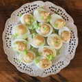 Deviled eggs with cod livers with leek on white plate. Rustic wooden table Royalty Free Stock Photo