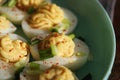 Deviled Eggs sprinkled with paprika and chopped green onion on a green plate on a woodene table . Top view Royalty Free Stock Photo