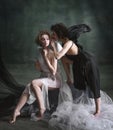 Devilish woman whispering to naive angel. Portrait of two women, angel and demon against dark, green, vintage background Royalty Free Stock Photo