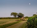 DEVON, ENGLAND - JULY 20 2021: A farmer making hay while the sun shines, working into the evening. Royalty Free Stock Photo