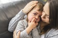 Devoted mother hugging and comforting her son on sofa