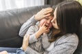 Devoted mother hugging and comforting her son on sofa