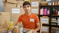 Devoted young hispanic man actively volunteering at a charity center, sitting at the table with a serious face, working diligently