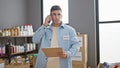 Devoted young hispanic man, a community volunteer, engrossed in a serious conversation on smartphone while diligently reading