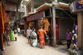 devotees, vendor shops with spiritual offering items and priests at the narrow street with over hanging old buildings