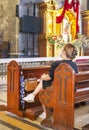 A devout Filipino worshiper,sits before the intricate golden altar of the Basilica of Saint Nino,Cebu\'s oldest church