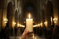 A devout hand holds a burning candle in a grand cathedral, illuminating a religious service