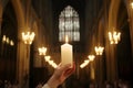 A devout hand holds a burning candle in a grand cathedral, illuminating a religious service
