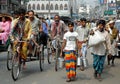 Dhaka, Bangladesh: A crowd of people walking or riding rickshaws along the street
