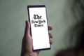 Dhaka, Bangladesh - 09 January 2024: Hands holding a smartphone with The New York Times logo on the screen. The New York Times is