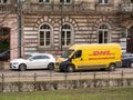 DHL package delivery service truck, van, vehicle parked on the street near a building, DHL German logistics courier company, urban