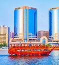 Dhow cruise boat on Dubai Creek against Deira Twin Towers, on March 1 in Dubai, UAE Royalty Free Stock Photo