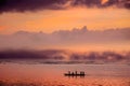 African Men pushing along with long poles a Dhow canoe in an orange sunset on the Indian Ocean near Mombasa, Kenya Royalty Free Stock Photo