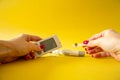 Diabet. Medical equipment. Medical concept. Close up of woman hands on yellow background using lancet on finger to check blood