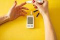 Diabet. Medical equipment. Medical concept. Close up of woman hands on yellow background using lancet on finger to check blood