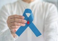 Diabetes Awareness ribbon for World diabetes day with red blood drop on blue bow color in person hand for supporting patient