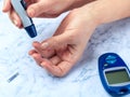 Diabetes checking blood sugar level. Woman using lancelet and glucometer at home