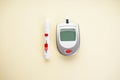 Digital glucometer and lancet pen on yellow background, close-up, flat lay. Diabetes concept. Blood glucose meter