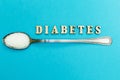 Diabetes inscription, spoon with sugar on a blue background