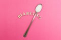Diabetes inscription, spoon with sugar on a pink background