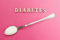 Diabetes inscription, spoon with sugar on a pink background, concept