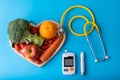 Diabetes monitor, diabetic measurement. World diabetes day concept with clean fruits in nutritionist`s heart dish.Healthy food or