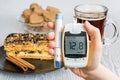 Diabetes and unhealthy eating concept. Hand holds glucometer and sweets. Royalty Free Stock Photo