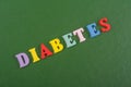 DIABETETES word on green background composed from colorful abc alphabet block wooden letters, copy space for ad text. Learning
