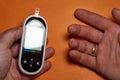 A diabetic checks his blood sugar. Close up man hands self-tested with a Lancet and a glucometer at home