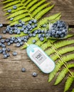 Natural blueberries, blood glucose meter and fern leaf on a wooden table