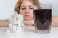 Diabetic woman is looking on glass with cola drink and heap of sugar. Unhealthy eating concept Royalty Free Stock Photo