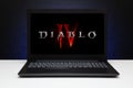 Diablo 4 game logo on the screen laptop computer on black textured wall with blue light.