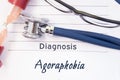 Diagnosis Agoraphobia. Psychiatric diagnosis Agoraphobia is written on paper, on which lay stethoscope and hourglass for measuring