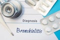 Diagnosis Bronchiolitis. Doctor`s stethoscope, electronic thermometer and two blisters of pills lying near pad with inscription of