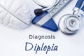 Diagnosis of Diplopia. Anatomical brain figure, neurological hammer and stethoscope lying on sheet of paper or book with the title