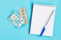 Diagnosis of the disease. Notebook with pen and pills on a blue background Royalty Free Stock Photo