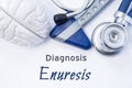 Diagnosis of Enuresis. Anatomical brain figure, neurological hammer and stethoscope lying on sheet of paper or book with the title