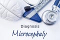 Diagnosis of Microcephaly. Anatomical brain figure, neurological hammer and stethoscope lying on sheet of paper or book with the t