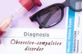 Diagnosis of Obsessive Compulsive Disorder. Hourglass, doctor glasses, mental status exam are near inscription Obsessive-Compulsiv