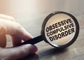 Diagnosis of Obsessive Compulsive Disorder under magnifying glass in hand. Causes, symptoms, diagnosis and treatment of