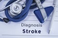 The diagnosis of stroke. Paper medical history with diagnosis of stroke, on which lie blue stethoscope, neurological hammer and pe