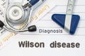 Diagnosis Wilson Disease. Neurological hammer, stethoscope and liver laboratory test lie on note with title of Wilson Disease. Con