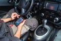 Diagnostics of car failures: an electrician in gray clothes is sitting in the car`s interior and reading the trouble Royalty Free Stock Photo