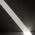 Diagonal beam of light illuminates a textured gray wall, casting a sharp shadow Royalty Free Stock Photo