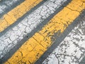 Diagonal cracked yellow and white paint lines on grey asphalt road texture, top view as grunge background or wallpaper Royalty Free Stock Photo